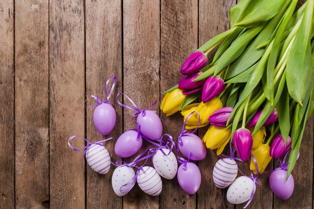 Vista superior de mesa con huevos de pascua y tulipanes