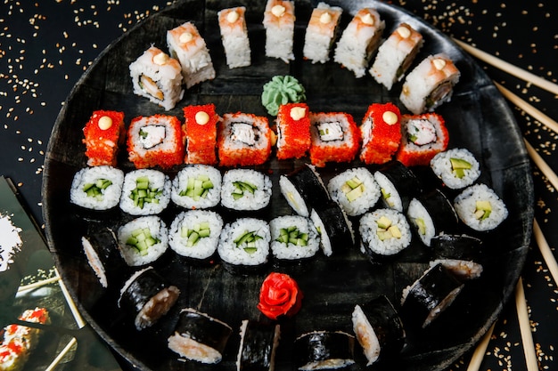 Vista superior mezclar rollos de sushi en un plato con wasabi y jengibre