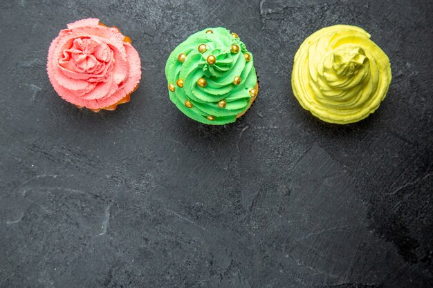 Vista superior de mini cupcakes coloridos fila horizontal en superficie oscura