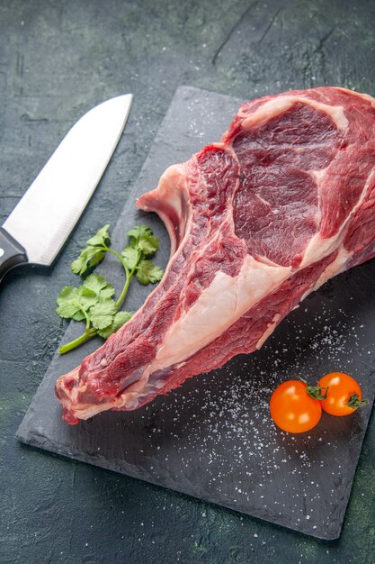 Vista superior de la mitad de la carne grande rebanada de carne cruda sobre una superficie oscura