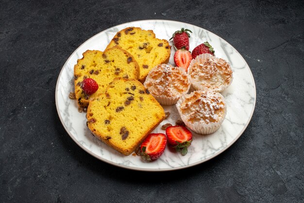 Vista superior de la mitad de deliciosas rebanadas de pastel con fresas rojas frescas y galletas en la superficie gris pastel hornear pastel de galletas azúcar galletas dulces