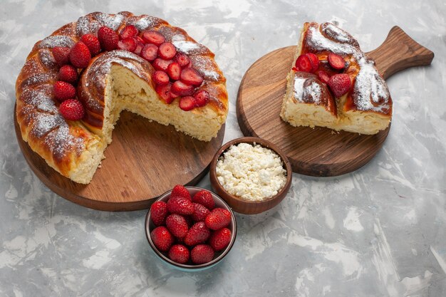 Vista superior de la mitad del delicioso pastel de fresa horneado y delicioso postre con requesón sobre superficie blanca