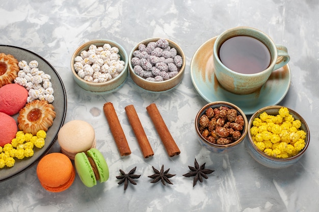 Vista superior de la mitad de los deliciosos pasteles con té de galletas y dulces en el escritorio blanco