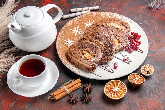 Vista superior de la mitad de deliciosos rollos de galletas con una taza de té en una mesa oscura pastel de pastel dulce