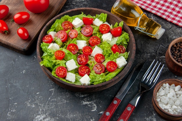 Foto gratuita vista superior de la mitad de la sabrosa ensalada de verduras con queso en rodajas, tomates y condimentos sobre fondo oscuro, comida, color, dieta, almuerzo, comida saludable