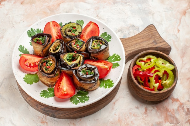 Vista superior de la mitad de sabrosos rollos de berenjena con tomates frescos y verduras