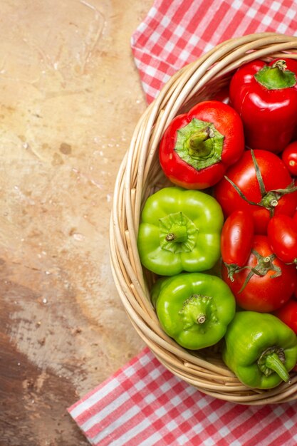 Vista superior de la mitad de los tomates pimientos verdes y rojos en una cesta de mimbre y una toalla de cocina sobre fondo ámbar