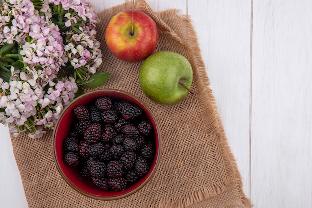 Vista superior de la mora en un recipiente con manzanas en una servilleta beige con flores