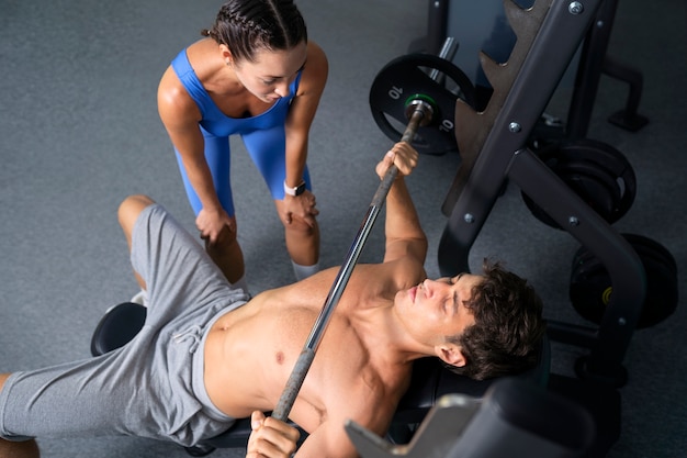 Vista superior mujer ayudando a hombre en el gimnasio