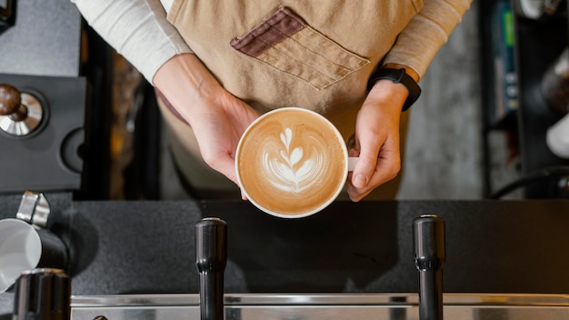 Vista superior de la mujer barista sosteniendo una taza de café