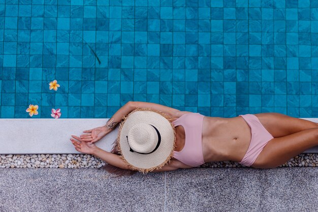 Vista superior de la mujer delgada en bikini en el borde de la piscina disfrutando de las vacaciones