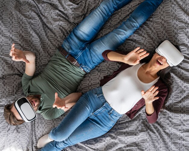 Vista superior de la mujer y el hombre con casco de realidad virtual en la cama