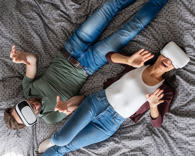 Vista superior de la mujer y el hombre con casco de realidad virtual en la cama