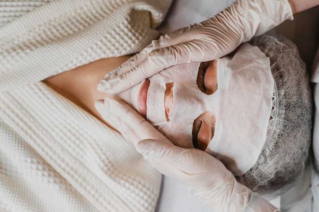 Foto gratuita vista superior de la mujer joven recibiendo un tratamiento con mascarilla para la piel