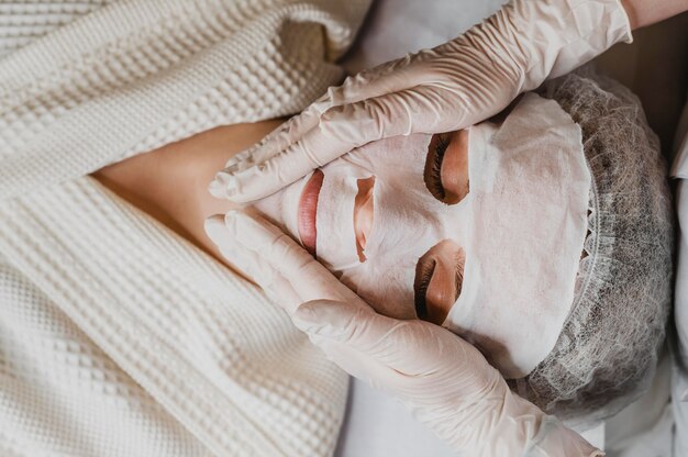 Vista superior de la mujer joven recibiendo un tratamiento con mascarilla para la piel