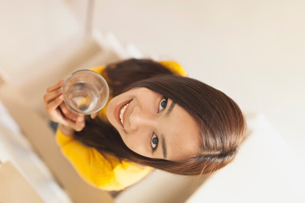 Vista superior de mujer joven con vaso de agua