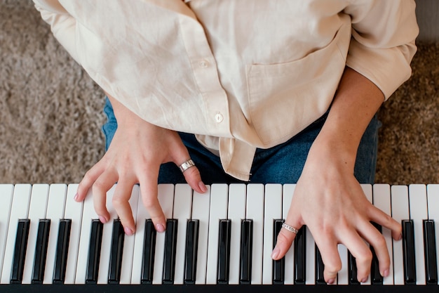 Vista superior de la mujer músico tocando el teclado del piano