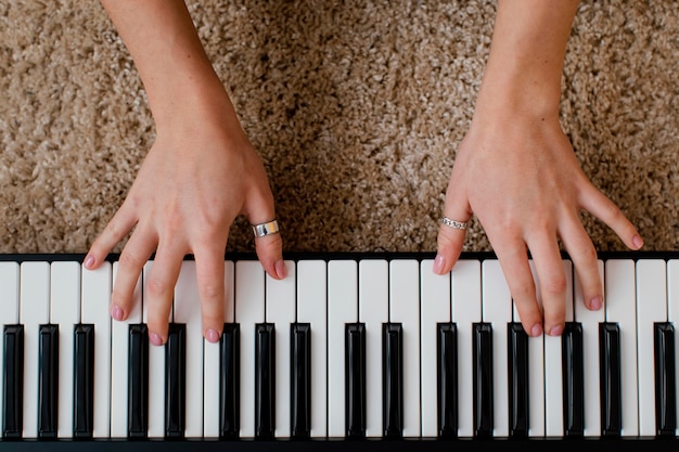 Vista superior de la mujer músico tocando el teclado del piano