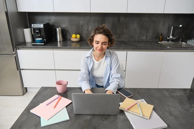 Vista superior de una mujer de negocios que trabaja desde casa una niña estudia remotamente en una computadora portátil se sienta en la cocina y mira