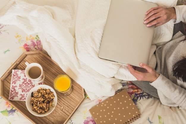 Vista superior de mujer con portátil y bandeja de desayuno