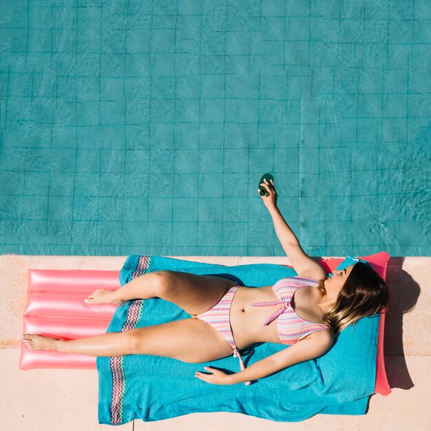 Vista superior de mujer relajando al lado de piscina