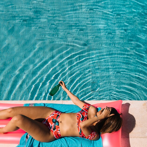 Vista superior de mujer relajando al lado de piscina