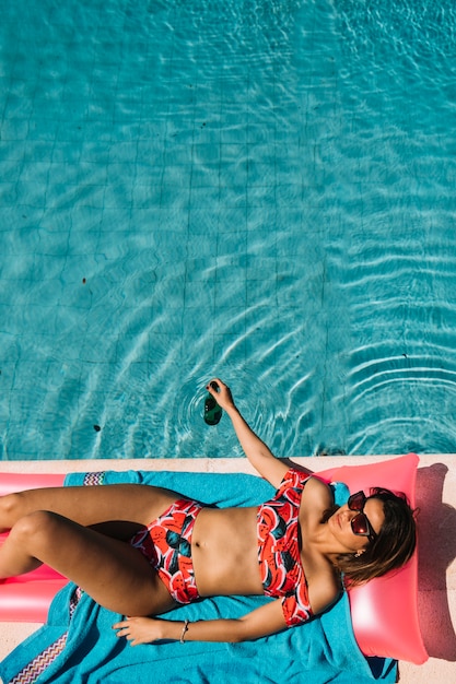 Vista superior de mujer relajando al lado de piscina