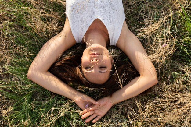 Vista superior de mujer relajante en la naturaleza sobre hierba