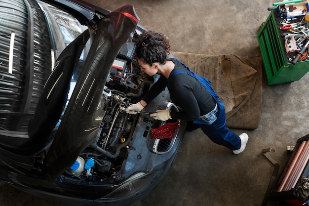 Vista superior mujer reparando coche