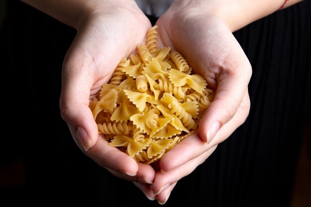 Una vista superior mujer sosteniendo pasta cruda y comida amarilla pasta italiana