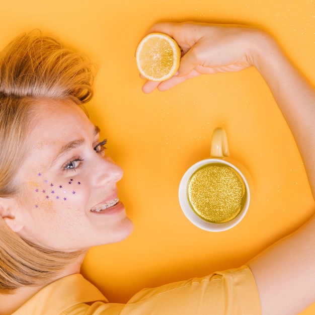 Foto gratuita vista superior de mujer con taza y limón en escenario amarillo