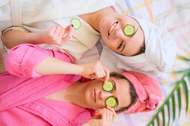 Vista superior de mujeres felices con rodajas de pepino en los ojos