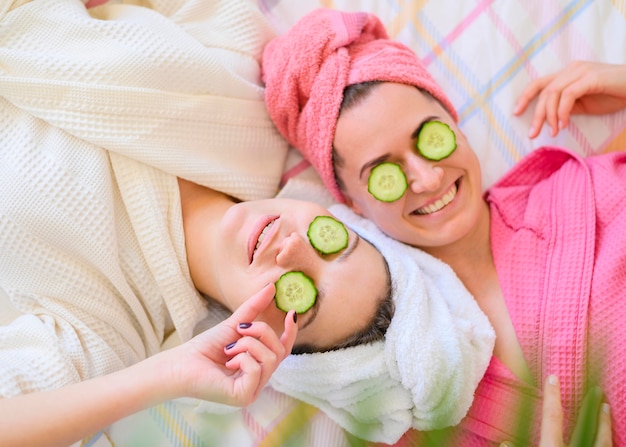 Vista superior de mujeres sonrientes con rodajas de pepino en los ojos