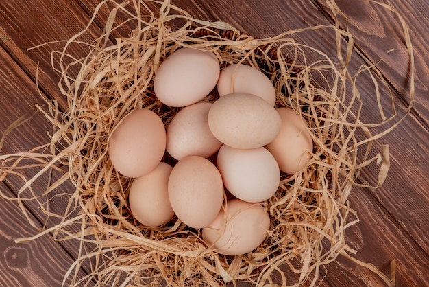 Vista superior de múltiples huevos de gallina en el nido sobre un fondo de madera