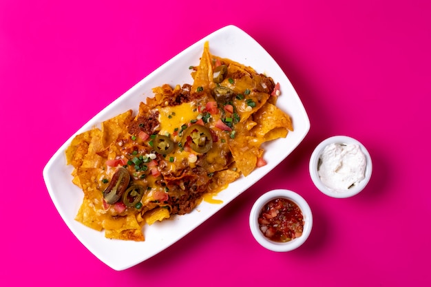 Vista superior de nachos mexicanos con carne picada encurtidos de queso derretido tomate jalapeño y cebolleta