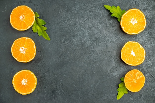 Foto gratuita vista superior de naranjas cortadas en fila vertical sobre fondo oscuro espacio libre