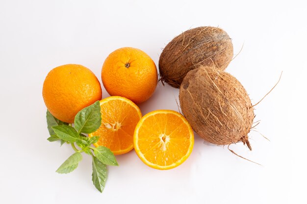 Vista superior naranjas enteras frescas jugosas y agrias junto con cocos en el fondo blanco frutas exóticas de color cítrico
