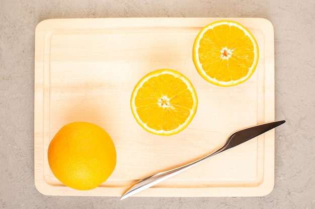 Foto gratuita una vista superior de naranjas frescas agrias maduras en rodajas y todo cítricos suaves vitaminas tropicales amarillo en el escritorio de crema