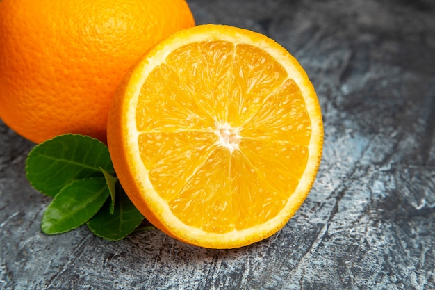 Vista superior de naranjas frescas enteras y cortadas por la mitad en el lado derecho del fondo gris