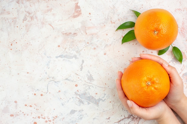 Vista superior de naranjas frescas en mano femenina y en superficie aislada brillante con espacio de copia