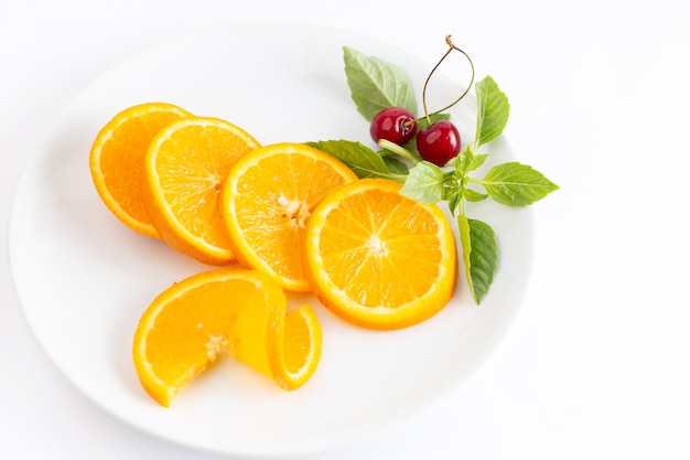 Vista superior de naranjas frescas en rodajas dentro de la placa blanca con un par de cerezas el fondo blanco jugo de color de frutas exóticas