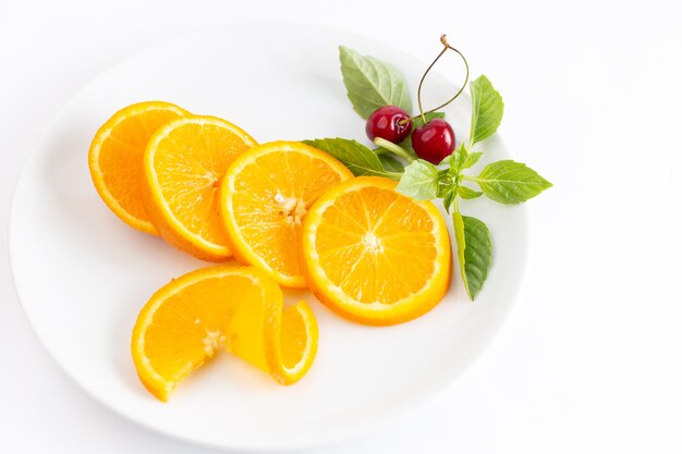 Vista superior de naranjas frescas en rodajas dentro de la placa blanca con un par de cerezas el fondo blanco jugo de color de frutas exóticas