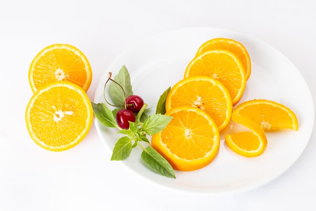 Vista superior de naranjas frescas en rodajas dentro de un plato blanco sobre el jugo de color de fruta de fondo blanco