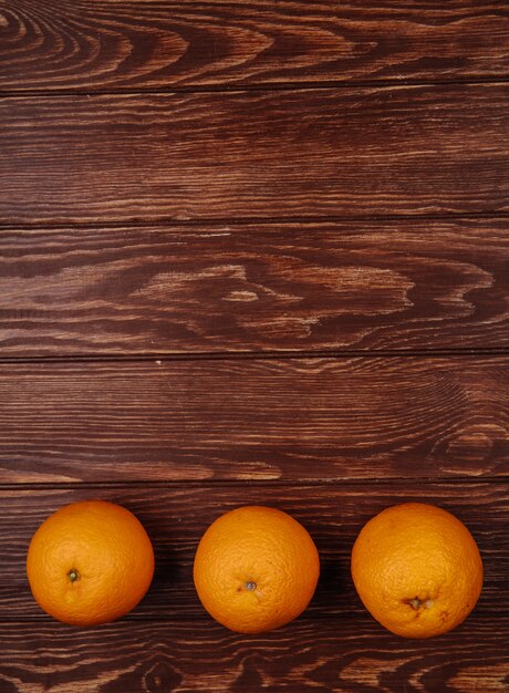 Vista superior de naranjas maduras frescas alineadas en una fila en madera con espacio de copia