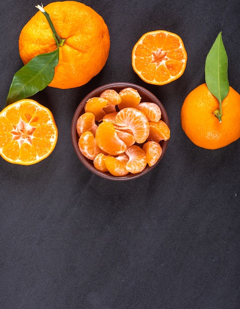 Vista superior de naranjas y mandarinas sobre superficie de piedra negra