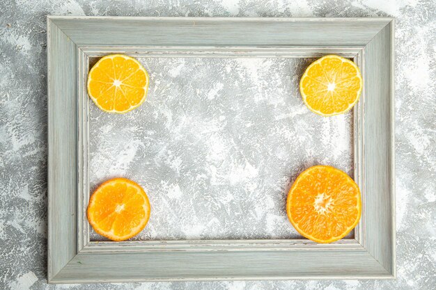 Vista superior de las naranjas en rodajas frescas cítricos suaves dentro del marco en la superficie blanca de frutas maduras tropicales frescas exóticas