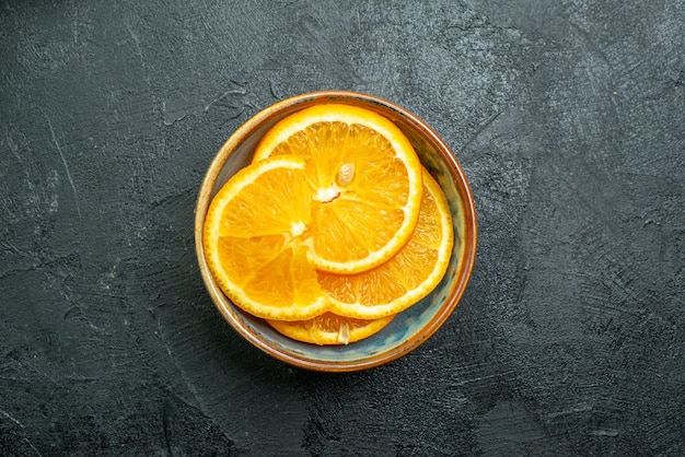 Vista superior de naranjas en rodajas frescas dentro de la placa en la superficie oscura de jugo de frutas tropicales exóticas cítricos