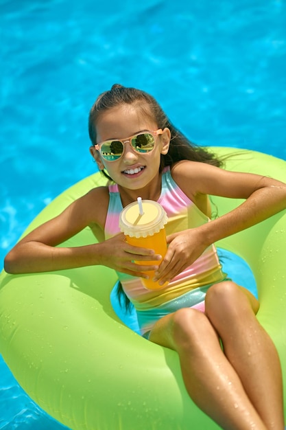 Vista superior de niña en anillo inflable con bebida