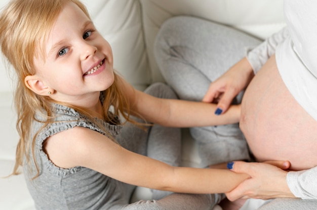 Foto gratuita vista superior niña jugando con vientre de madre embarazada