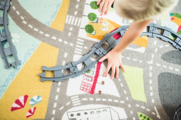 Vista superior de niño jugando con las vías de un tren